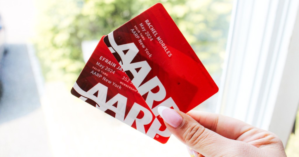 يد تحمل بطاقتي AARP باللون الأحمر