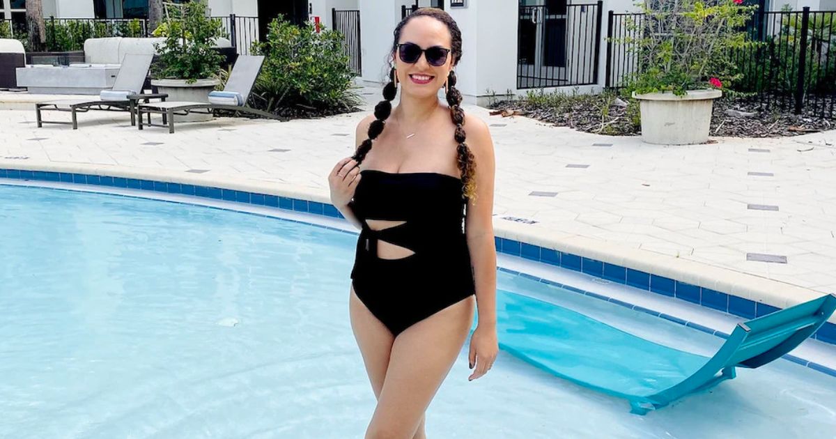 a woman in the shallow end of a pool wearing a black one piece swimsuit