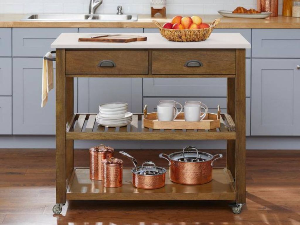 a rolling kitchen island in natural wood with food and pots and pans