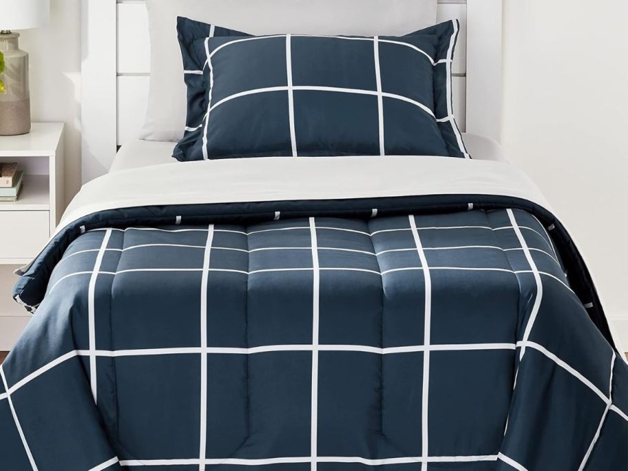 A bed with an Amazon Basics 5-Piece Comforter Set TwinTwin XL in Navy