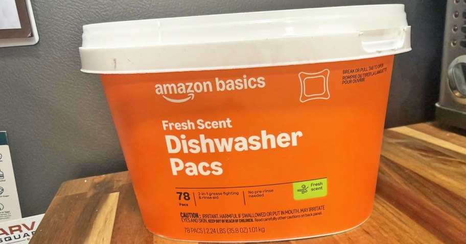 orange container of Amazon Basics Dishwasher Detergent Pacs on a wood table