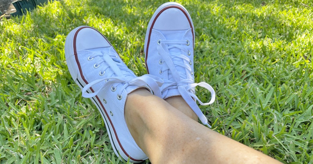 wearing pair of white canvas sneakers in grass