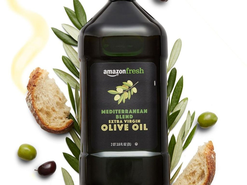 A green bottle of Extra Virgin Olive Oil on a bed of herbs