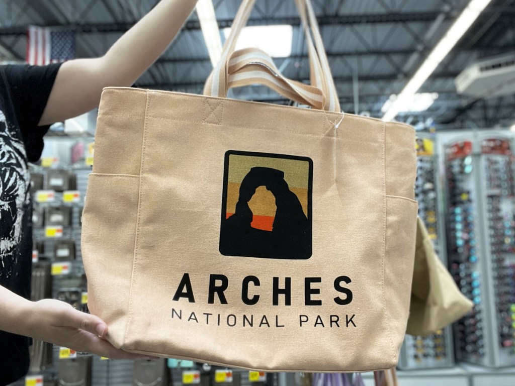 holding up a tote bag with arches national park design on it