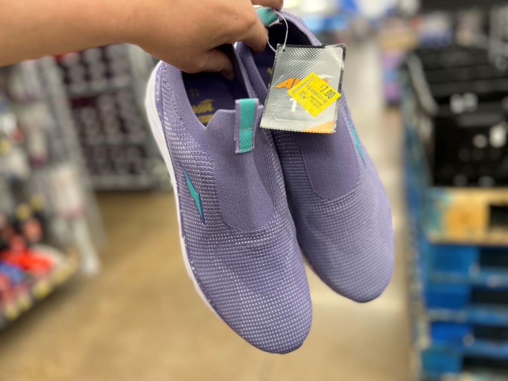 Hand holding a pair of purple shoes at Walmart
