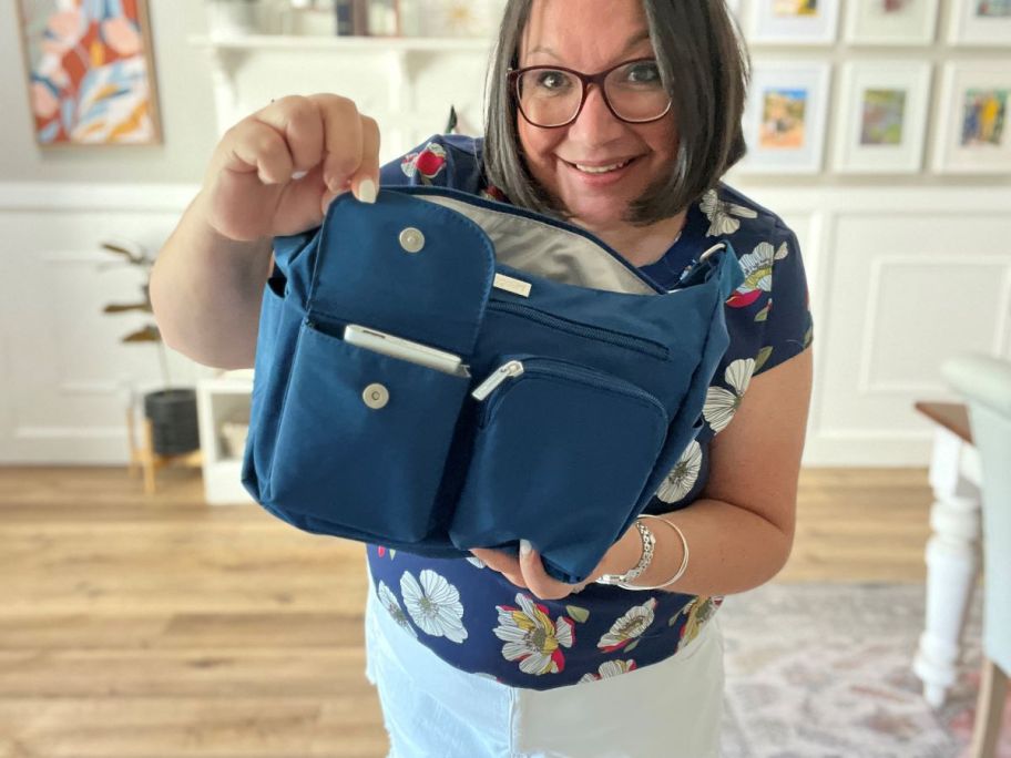 Woman holding open a flap on a blue purse