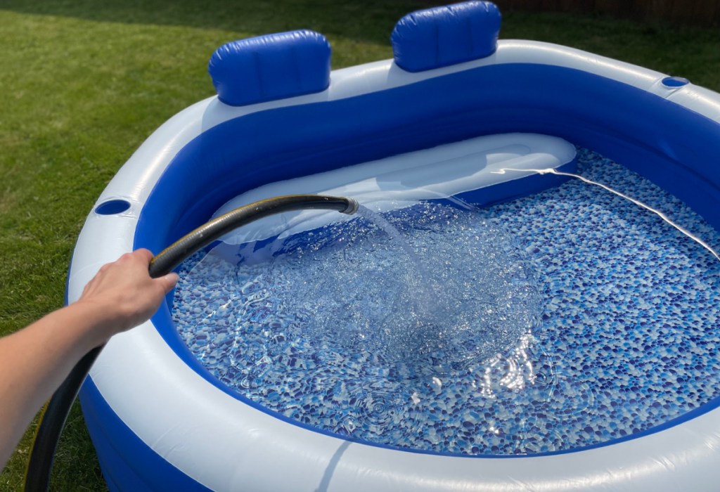 woman using a hose to fill up her Bestway Splash Paradise Inflatable Family Pool