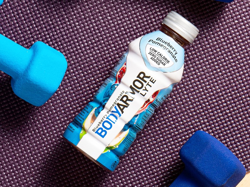 blue and white bottle of Body Armor Lyte near hand weights