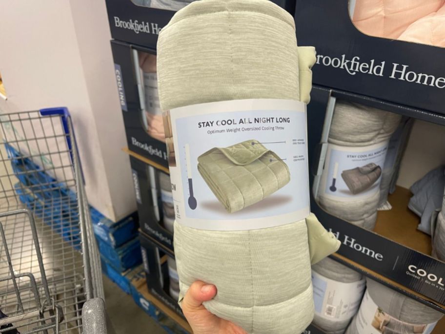 A person holding a Brookfield Home Cooling Throw in tan in the store