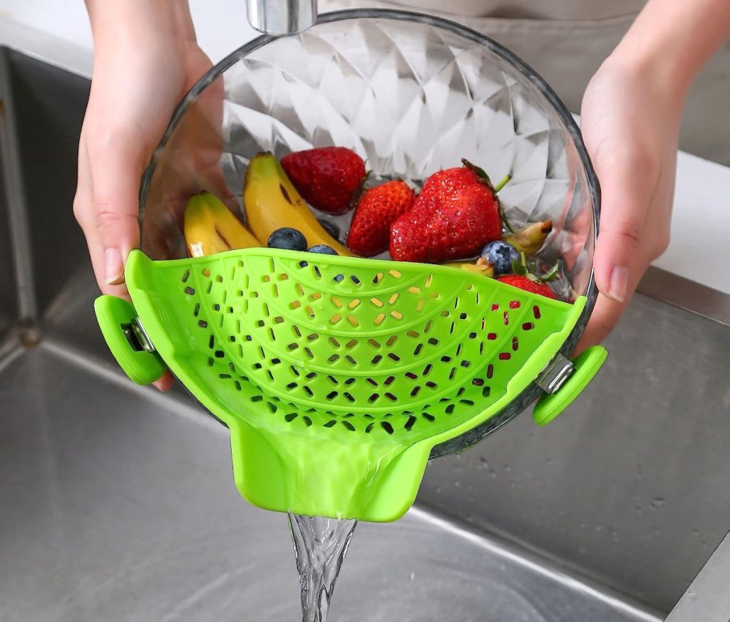 Person using a clip on colander to strain fruit