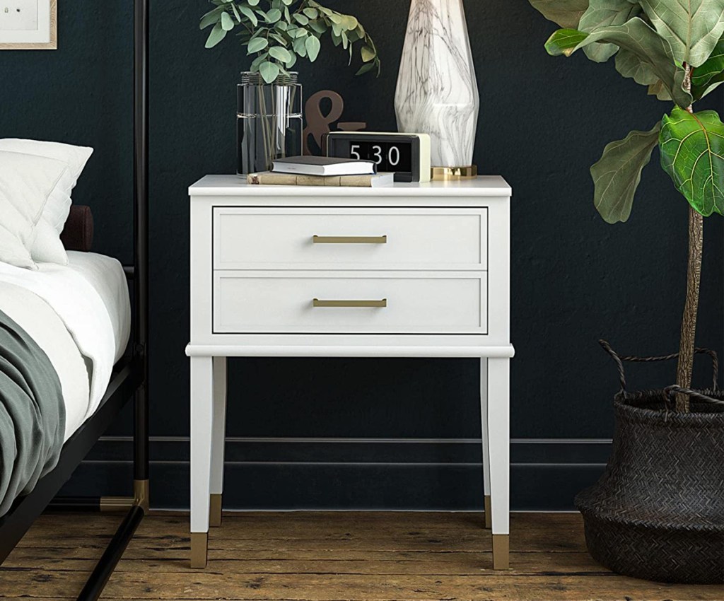 white end table with two drawers next to bed