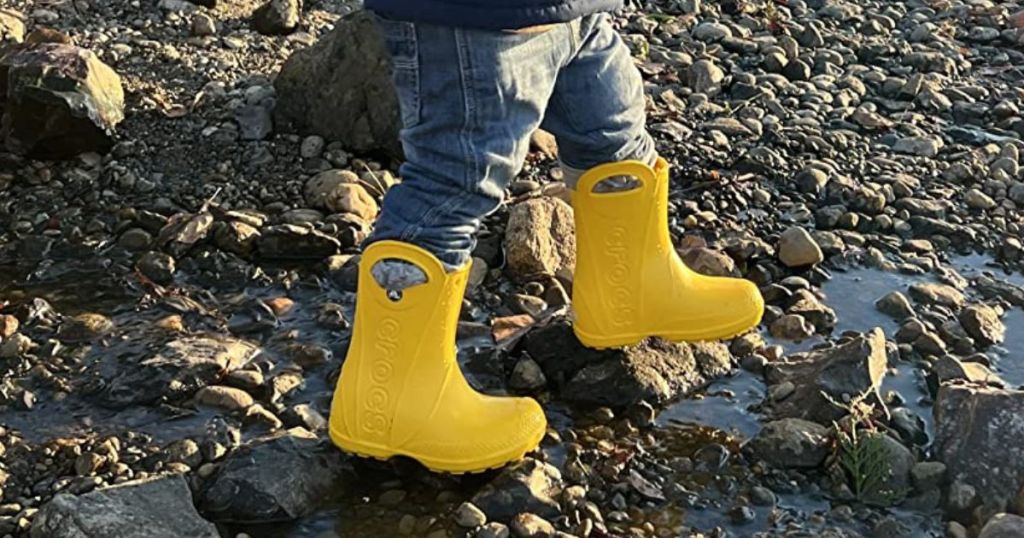 Toddler wearing Crocs rain boots to walk on rocky terrain
