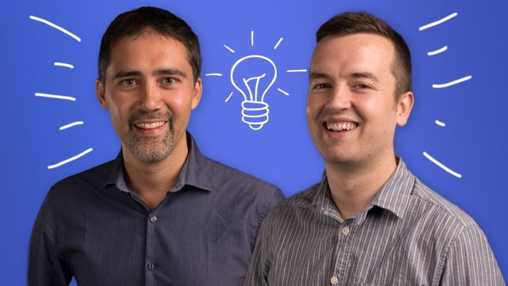 Two men standing together with a drawn image of a lightbulb between them