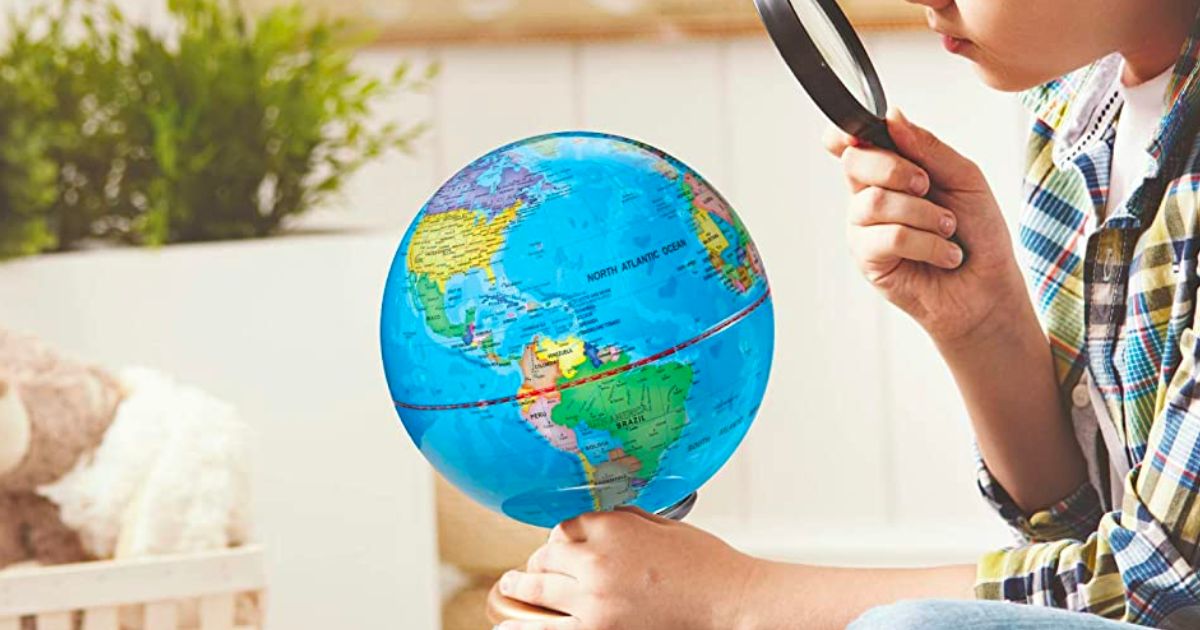a boy looking through a magnifying glass at a Discovery kids globe