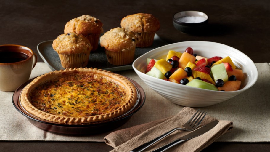 quiche, fruit, and muffins on table