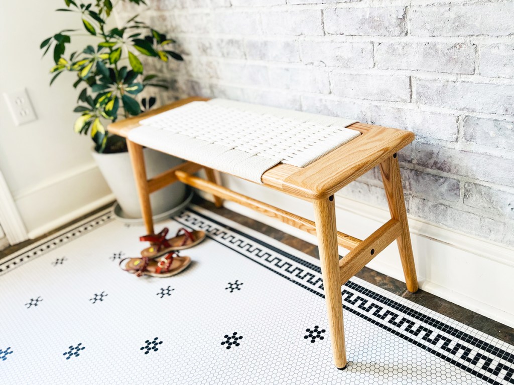 wood bench with white woven top in entry way with sandals below it