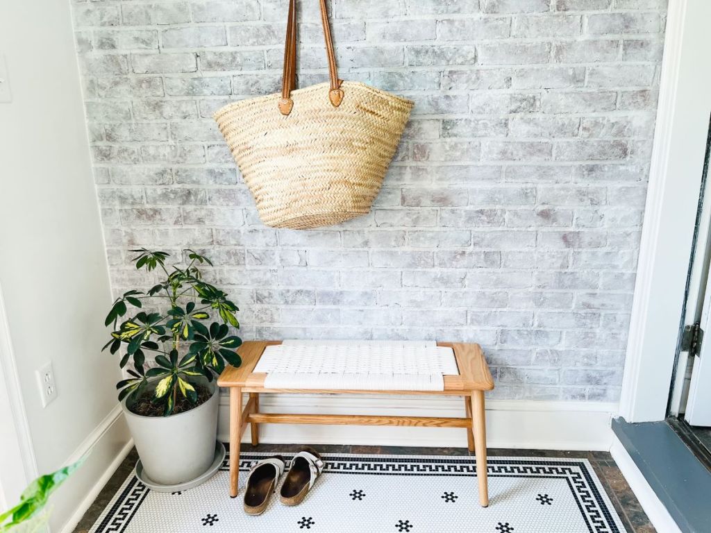 Room with a plant, small bench, and a bag hanging above the bench