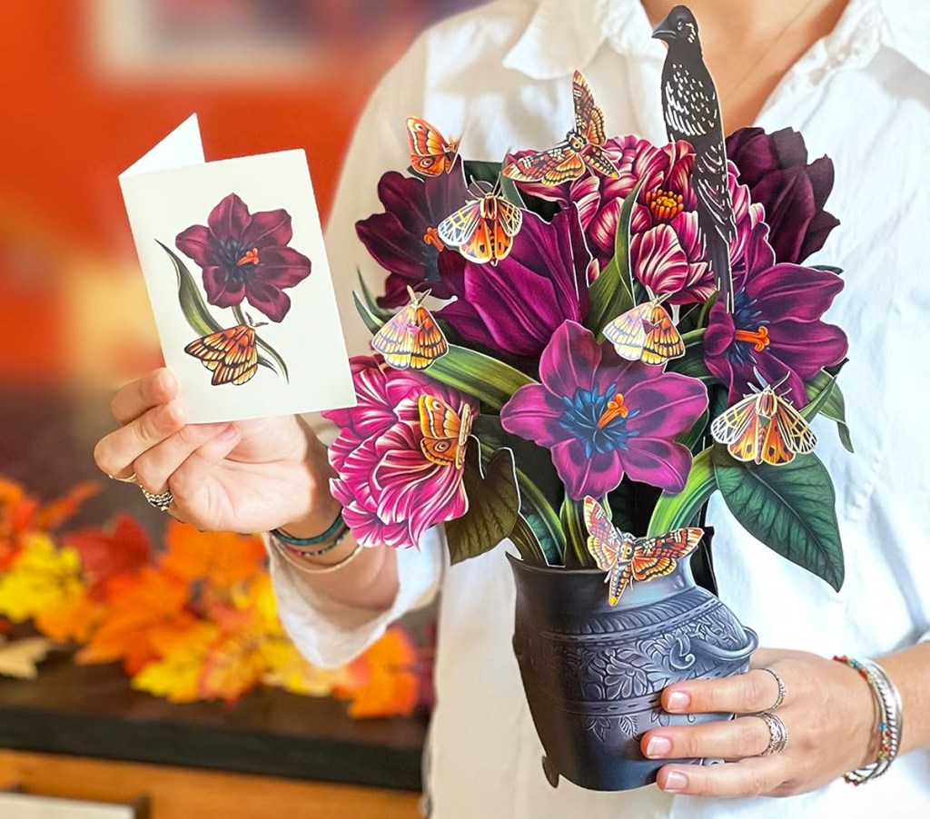 woman holding a bouquet of purple paper flowers and a matching card