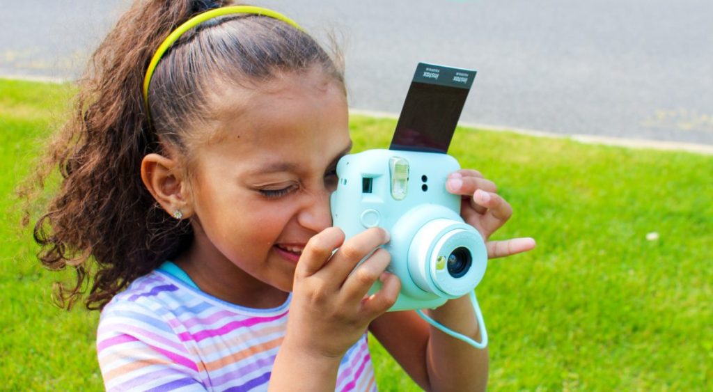 A young girl using her Fuji Instax Mini 12 Camera