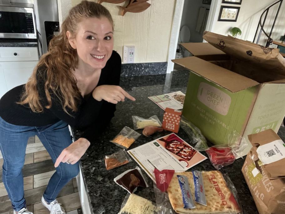 woman standing and pointing at the contents of a Green Chef Meal delivery box