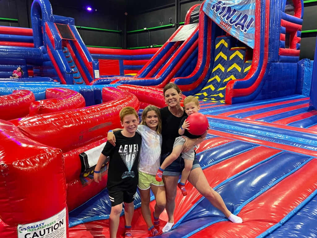 family standing in middle of blue and red inflatable jump park