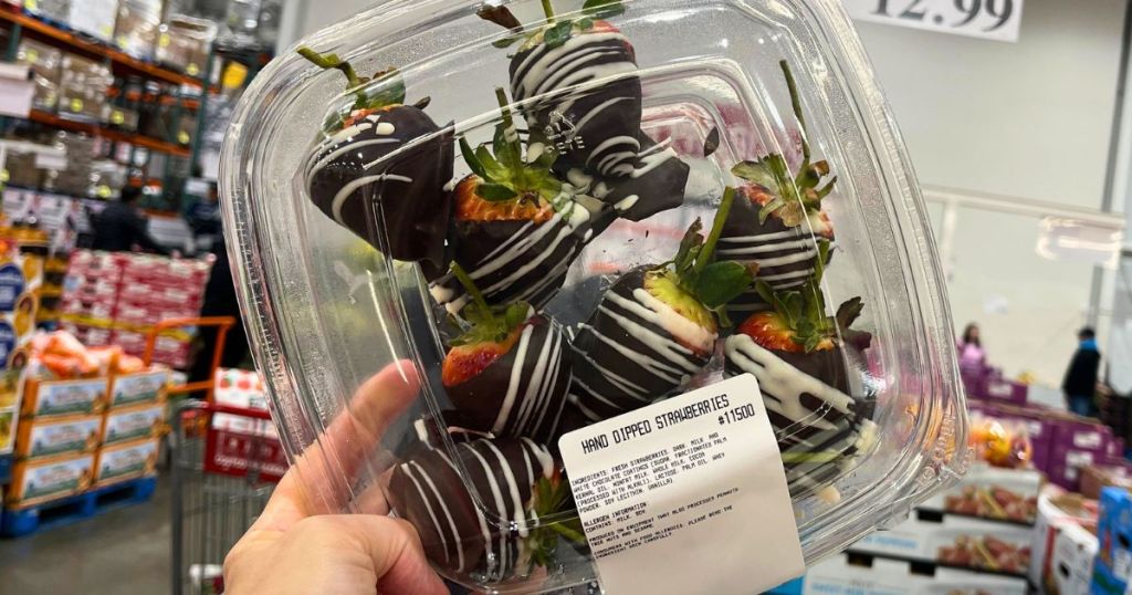 hand holding a plastic container of chocolate covered strawberries at Costco
