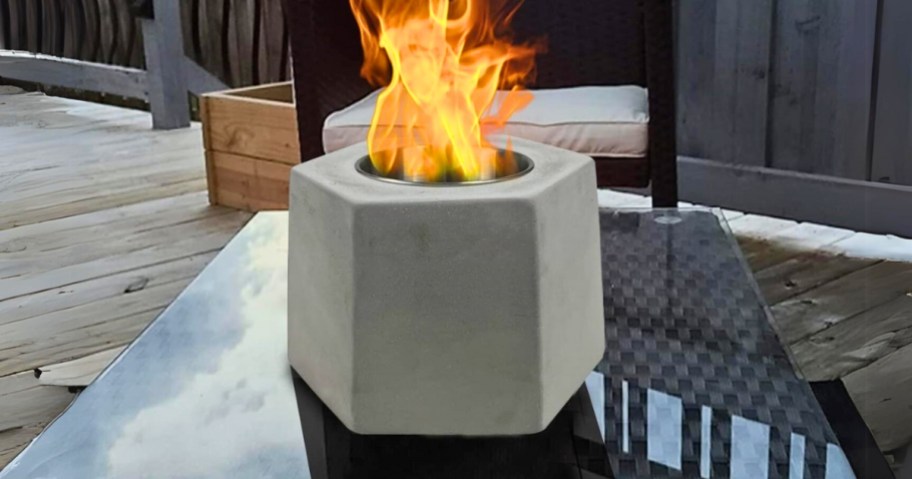 white mini tabletop firepit lit with fire on an outdoor table