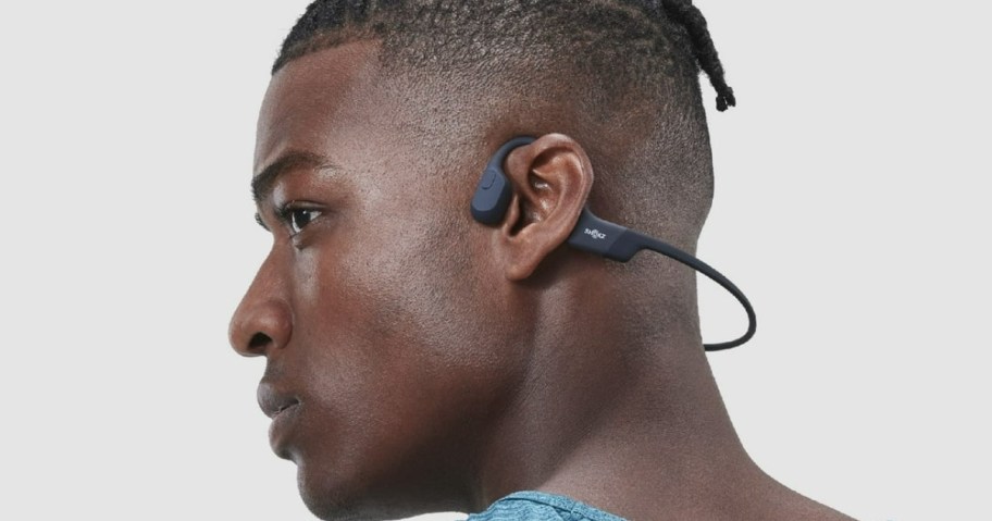 man wearing a pair of black over ear headphones that go around the back of hisr neck instead of over his head