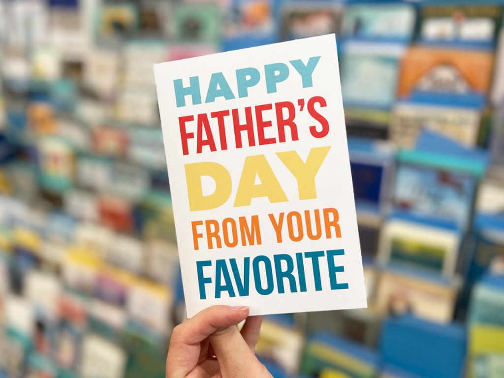 holding a card that says happy fathers day from your favorite