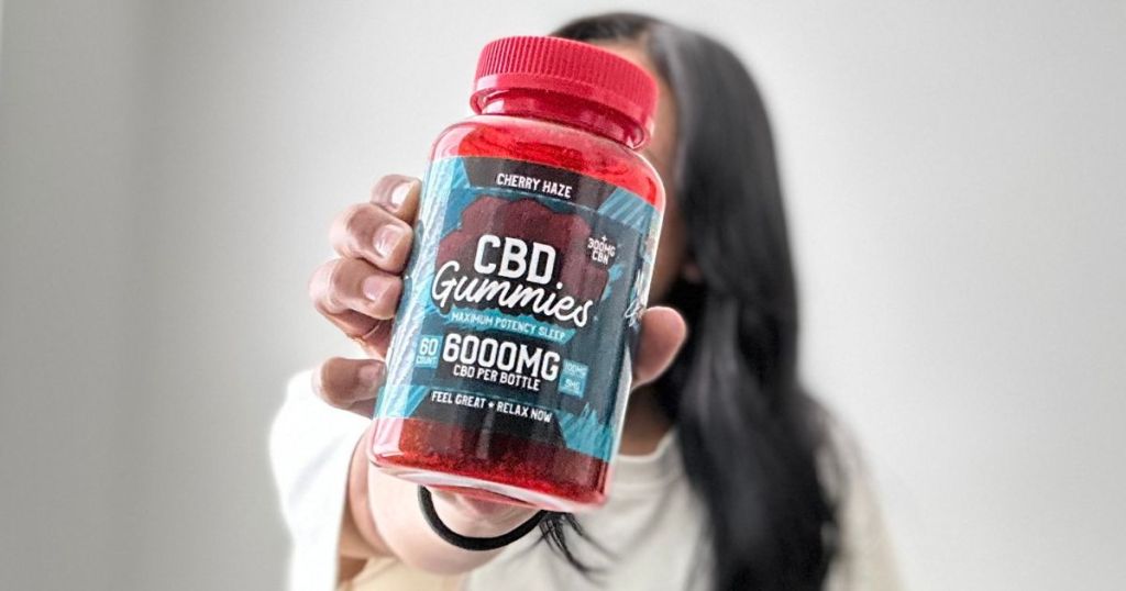 Woman holding a bottle of Hemp Bombs CBD Sleep Gummies in front of her face