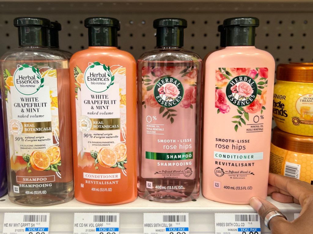 woman grabbing Herbal Essences Smooth Conditioner from store shelf