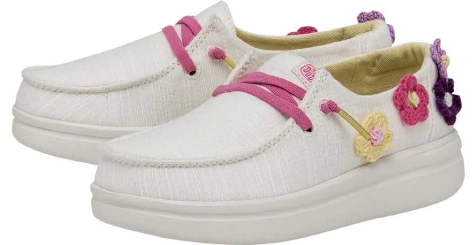 Pair of white Hey Dude shoes with pink laces and flowers on the back