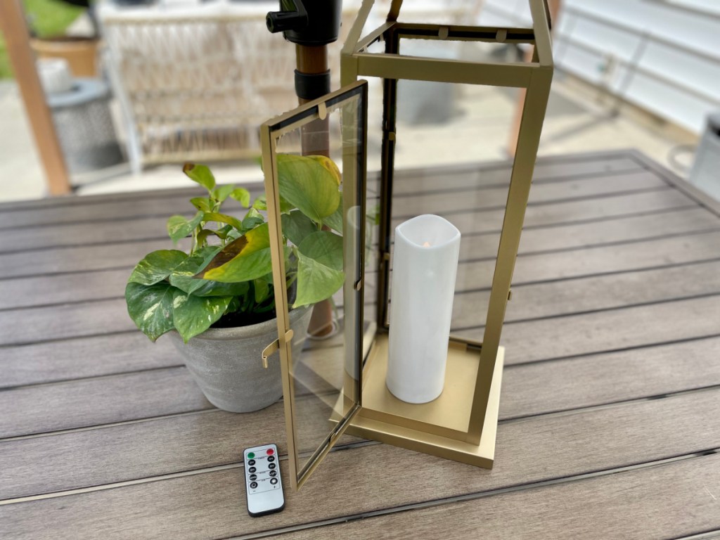 A metal lantern with candle and remote control displayed on an outdoor table