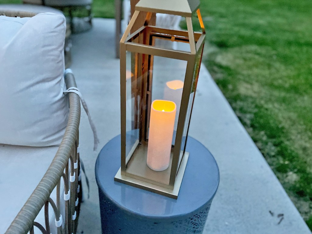 A glowing outdoor lantern sitting on an outdoor side table at night