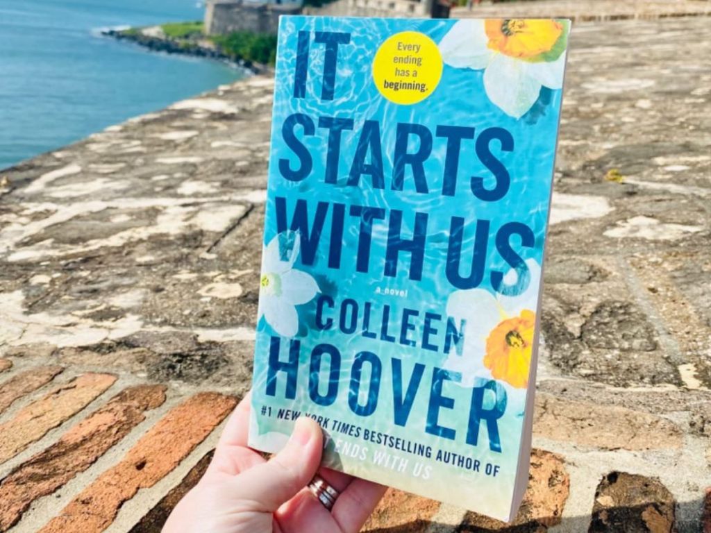 hand holding up It Starts With Us by Colleen Hoover