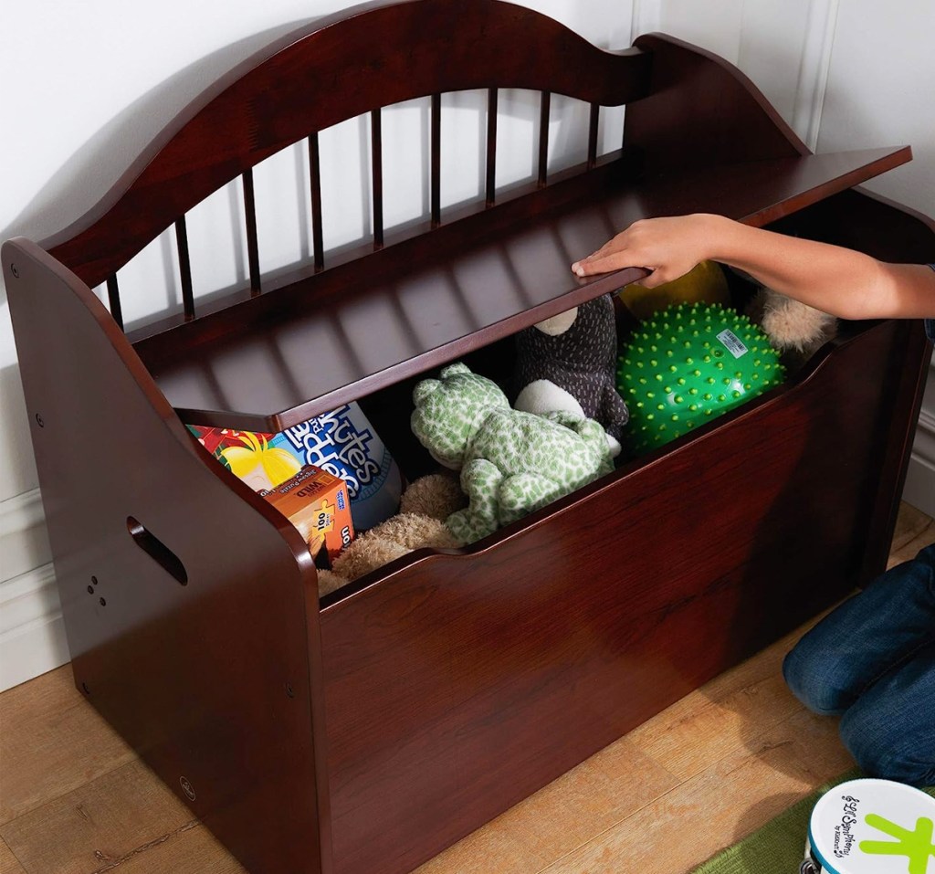 child lifting lid on brown wood toy box bench
