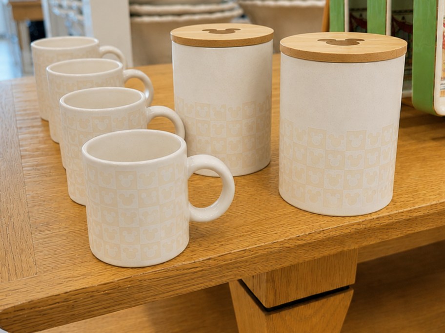 white checkered mickey mouse themed mugs and canisters on wood table