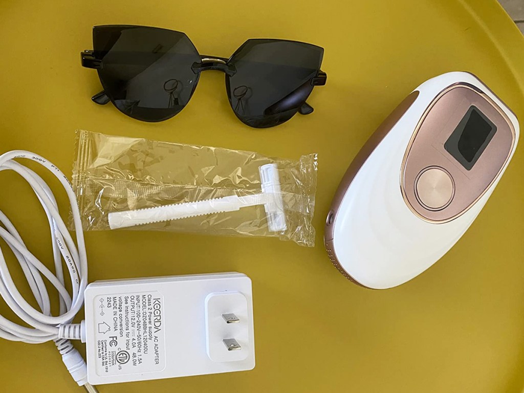 sunglasses, razor, charger, and ipl hair remover device on yellow table