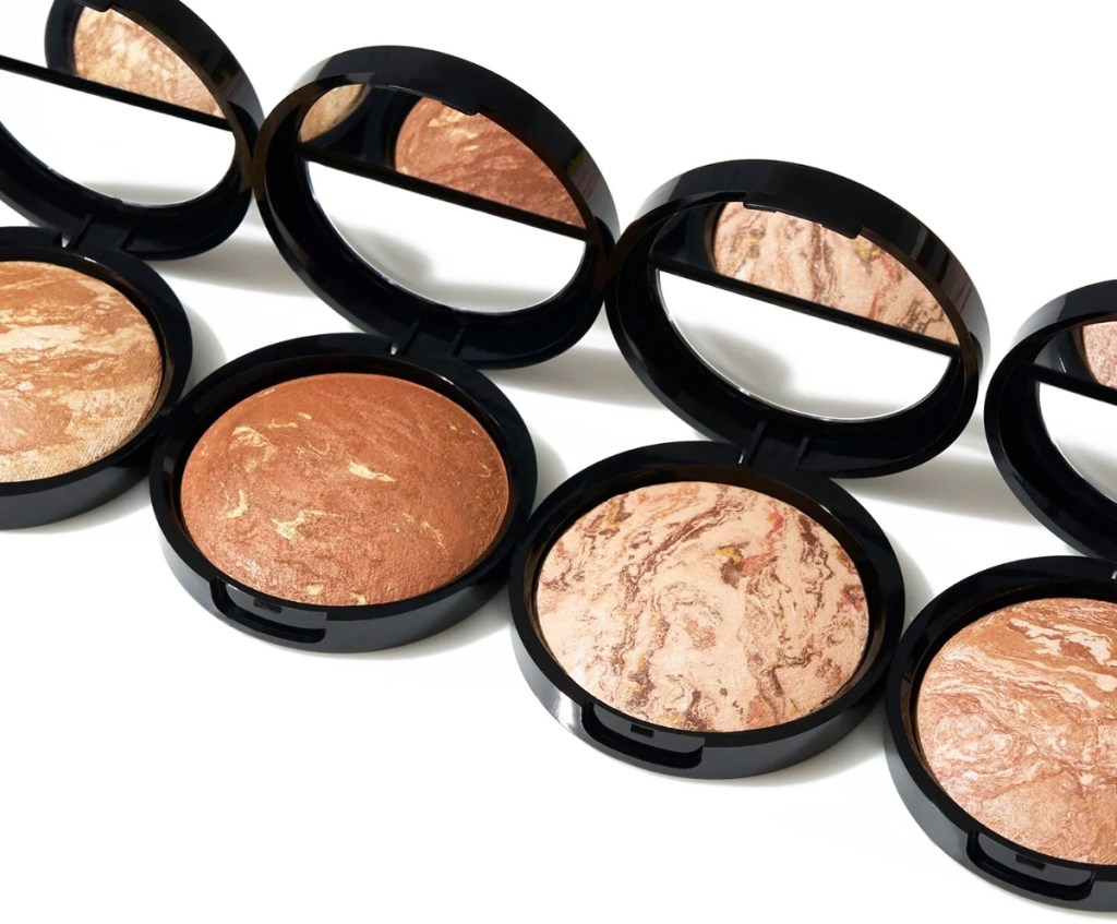 four opened compacts of laura geller bronzers