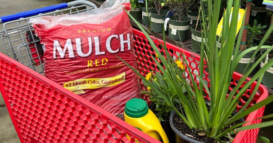 red Lowe's cart with a bag of mulch, preen, and plants in it