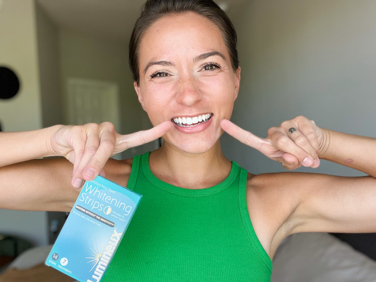 Woman pointing to the results of her Lumineux Teeth Whitening Strips, one of the top best beauty products of 2023.