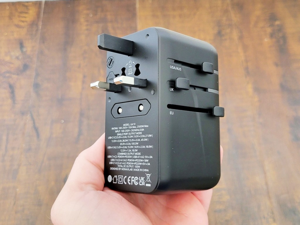 hand holding a black universal plug adapter