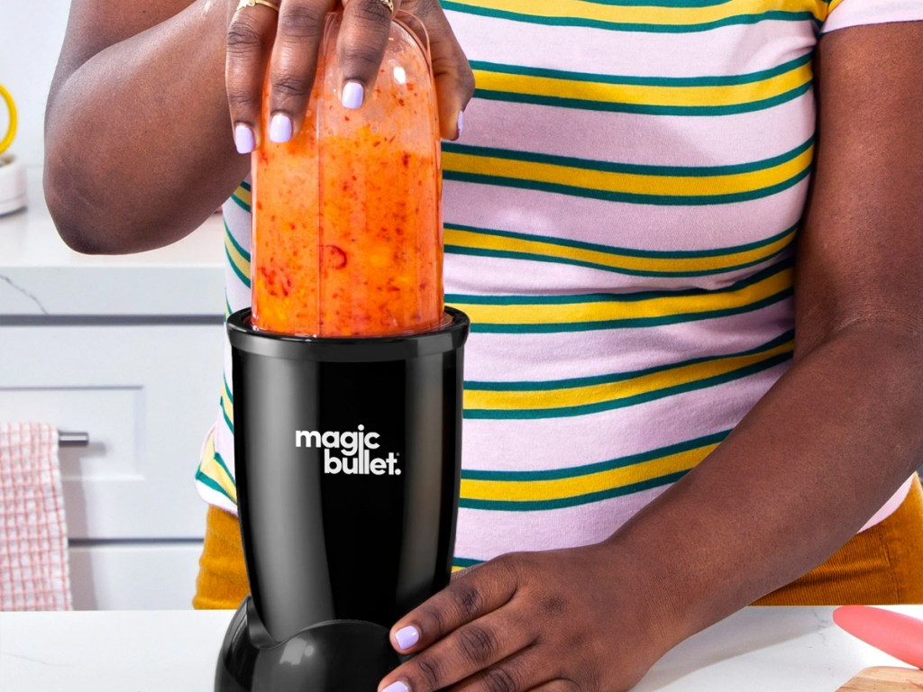 woman using magic bullet to blend orange smoothie