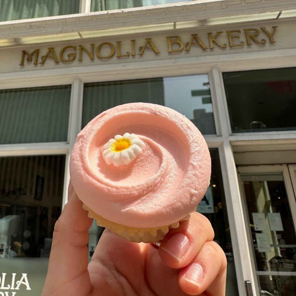 hand holding a cupcake outside of magnolia bakery