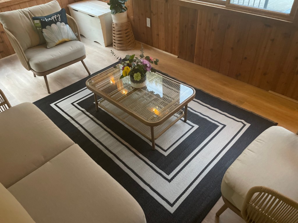 A gray outdoor rug from Walmart on the floor of a sunroom.
