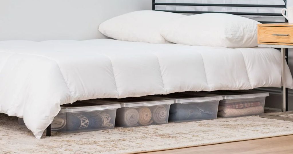 A bed with clear storage containers underneath 