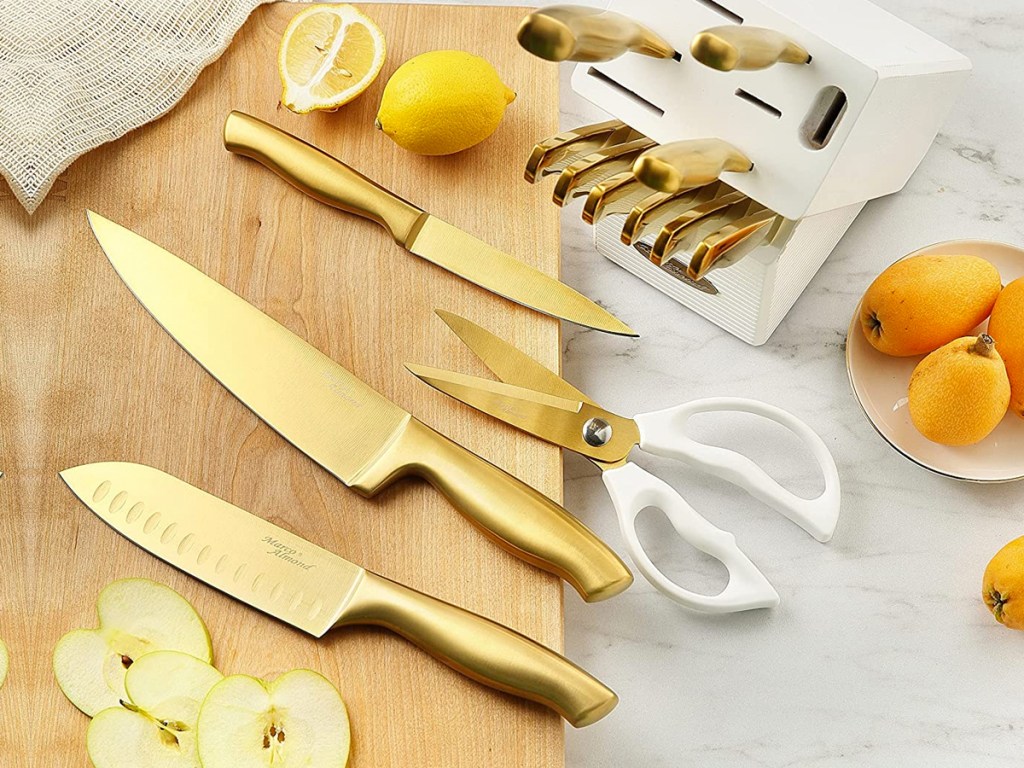 gold kitchen knife set on a wood cutting board