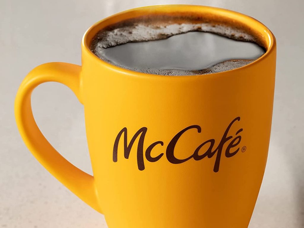 Yellow coffee cup that says McCafe on it with coffee in it