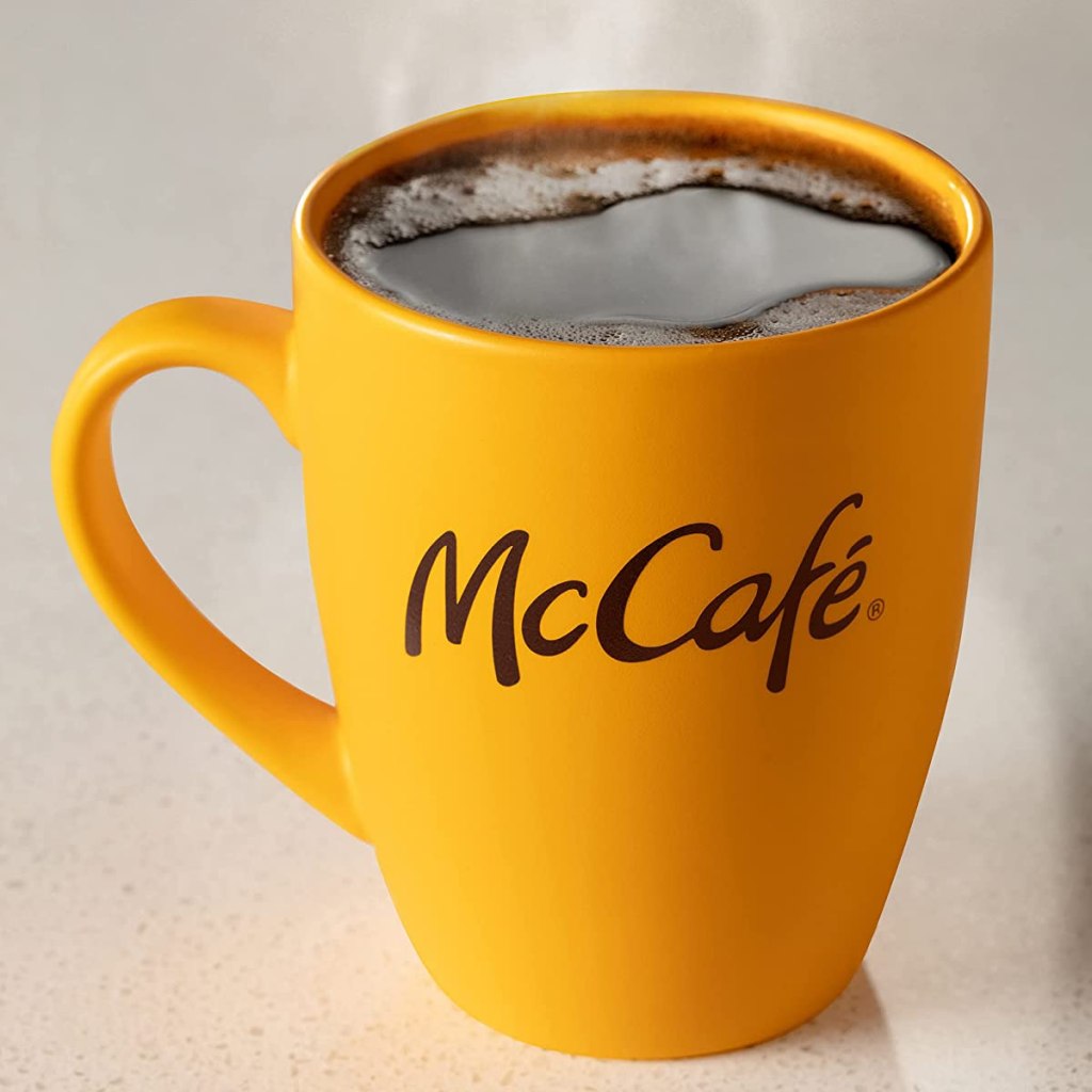 Yellow coffee cup that says McCafe on it with coffee in it