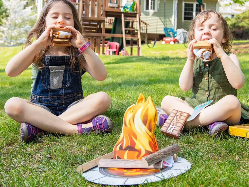 two girls sitting on grass eating pretend smores